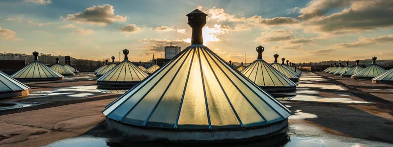 The roof of Temple Works at sunset. Image shows conical windows and puddles of water.